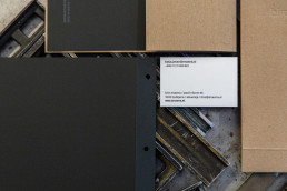 Business card and letterhead mockup for Enaena featuring minimalist design with dark grey and kraft brown paper materials on
