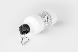 White water bottle with black text design and black cap with carabiner clip, lying on white background