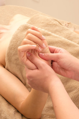 Hand massage therapy session with gentle finger pressure techniques on palm in warm, soft lighting