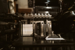 Vintage seismograph machine with paper recording strip in warm sepia tones, displaying scientific monitoring equipment for lo