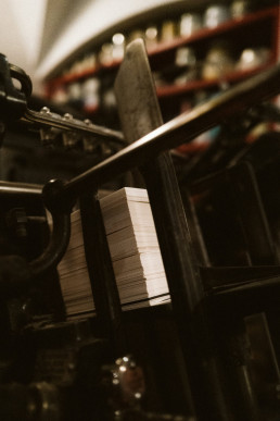 Sepia-toned photograph showing stacks of white business cards or paper in black plastic trays with blurred shelving in backgr