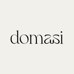 Logo for domasi featuring lowercase black serif typography on a light beige background with elegant, minimalist styling