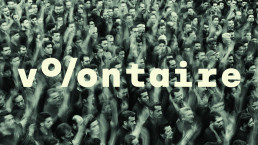 Volontaire logo in cream lettering overlaid on black and white photograph of dense crowd with raised arms