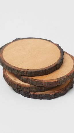 Stack of three rustic wood slice coasters with natural bark edges and smooth light wood surfaces