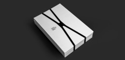 White minimalist book or publication mockup with black elastic bands, featuring clean typography on covers against dark backg