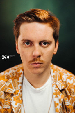 Logo for European Actors featuring portrait of man with reddish hair and mustache wearing orange patterned jacket over white