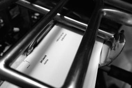 Black and white photograph showing nomia branding materials in a metal tray, featuring clean minimal typography on white pape