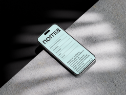 Mobile mockup showing nomia website with mint green background, minimalist navigation menu and Slovenian text on concrete sur
