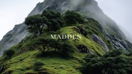 Madden logo in white serif font overlaid on misty green mountain landscape with lush vegetation and dramatic rocky cliffs.